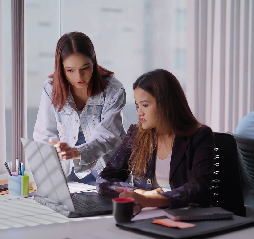 Women collaborating over laptop in office